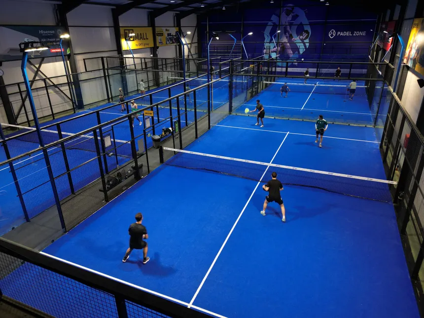 The indoor padel courts at Padel Zone Prishtina seen from above, several matches under way