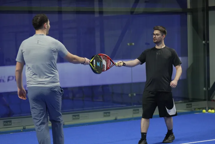 Two players tapping rackets after a game at Padel Zone