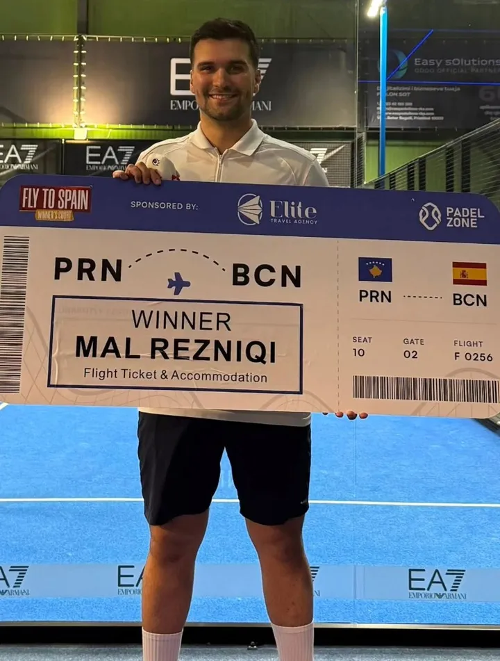 Mal Rezniqi holding an oversized boarding pass from Prishtina to Barcelona after winning the first Fly to Spain season