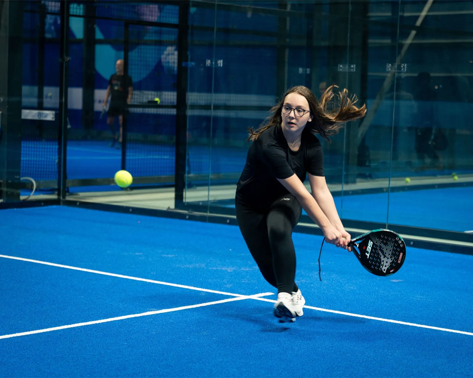 A girl from the junior academy reaching low for a ball on court