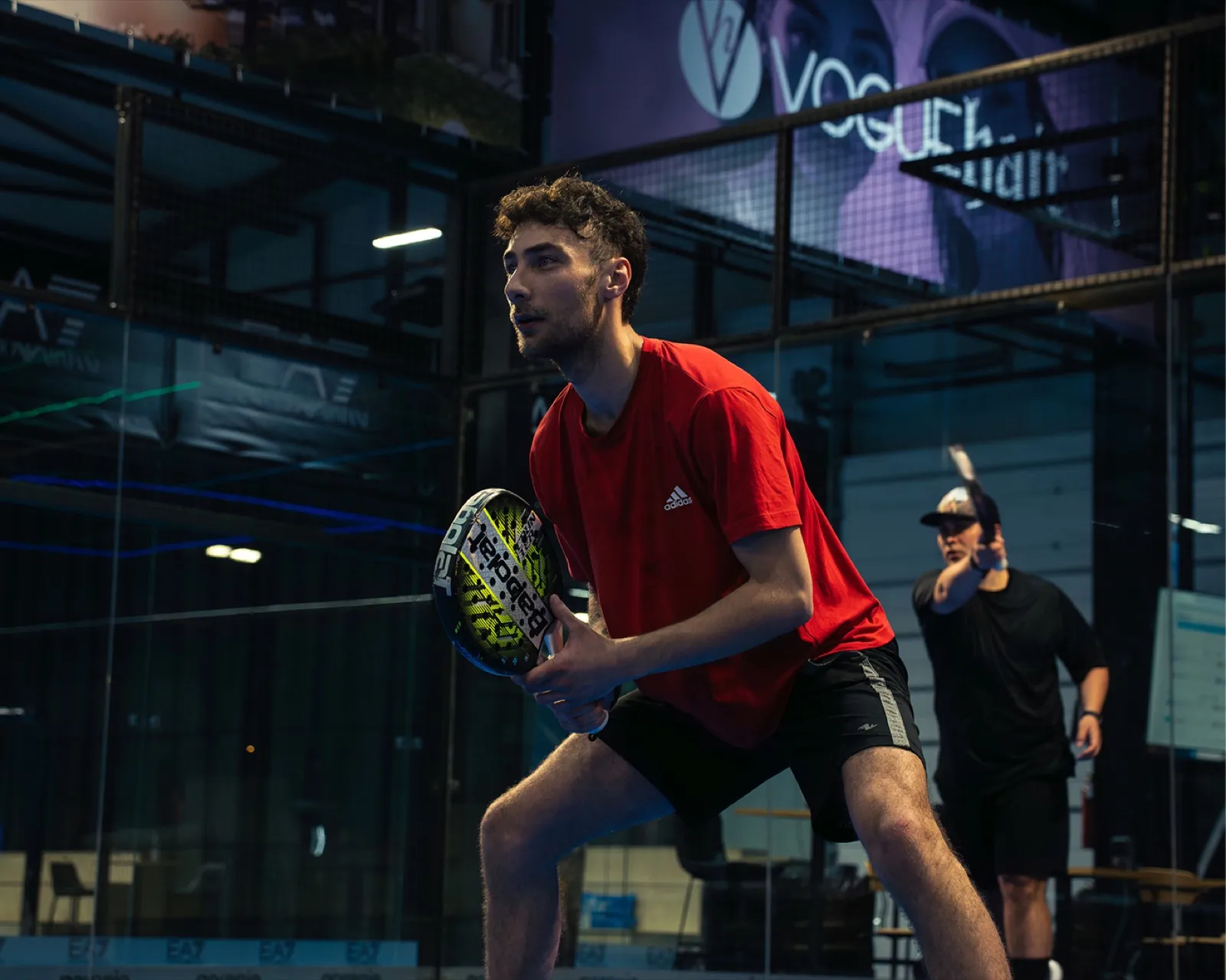 Padel player preparing to hit the ball in front of the glass wall at Padel Zone Prishtina