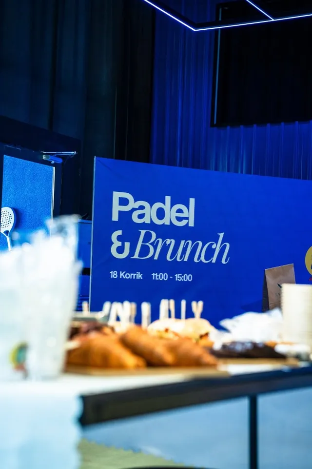 The Padel & Brunch banner beside the courts, with the food tables behind it
